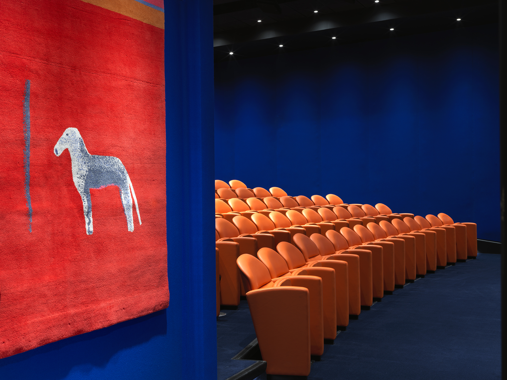 The entry to the state-of-the-art screening room with 130 comfortable leather seats in bright coral and electric blue walling.